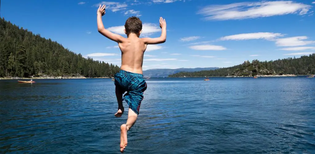 young boy jumping in lake tahoe near fannette island
